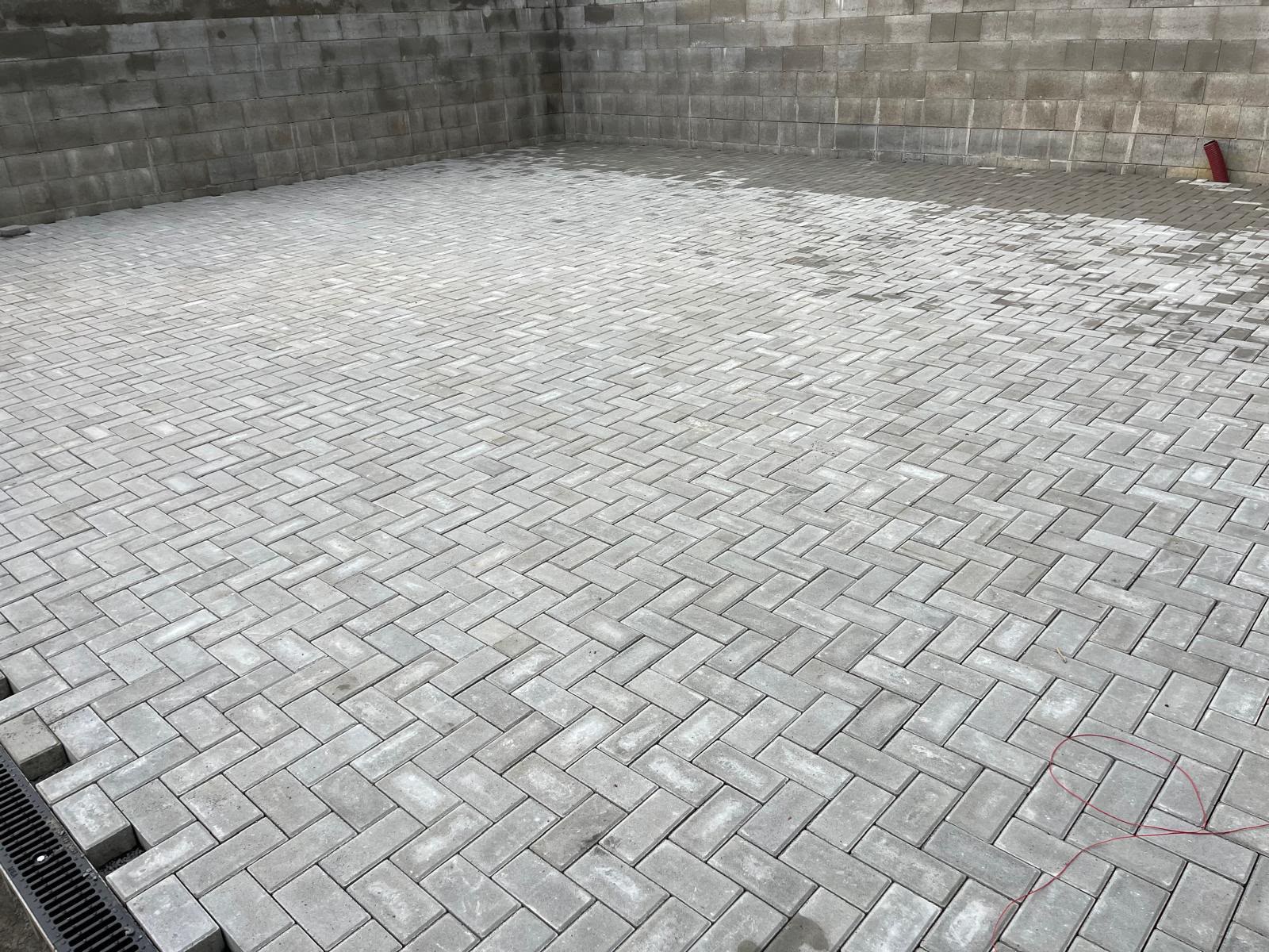 Zámková dlažba ve vzoru rybí kost u opěrné stěny