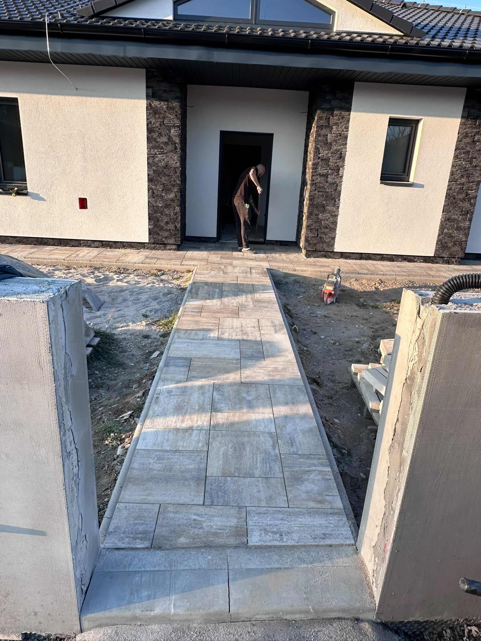 Chodník z velkoformátové dlažby vedoucí ke vstupu do rodinného domu během realizace