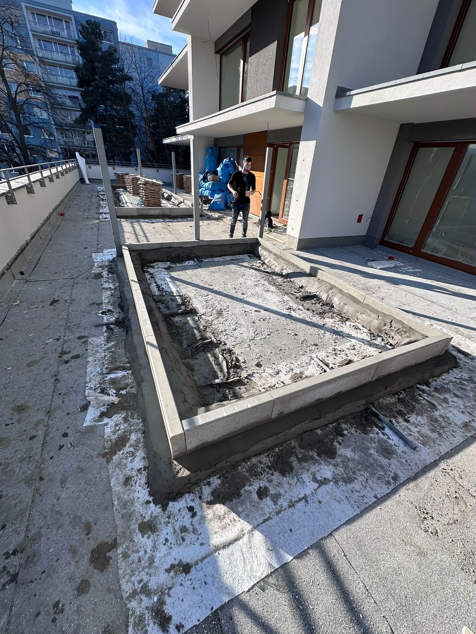 Osazené kamenné obrubníky ohraničující připravovanou plochu na terase u novostavby během zimních prací
